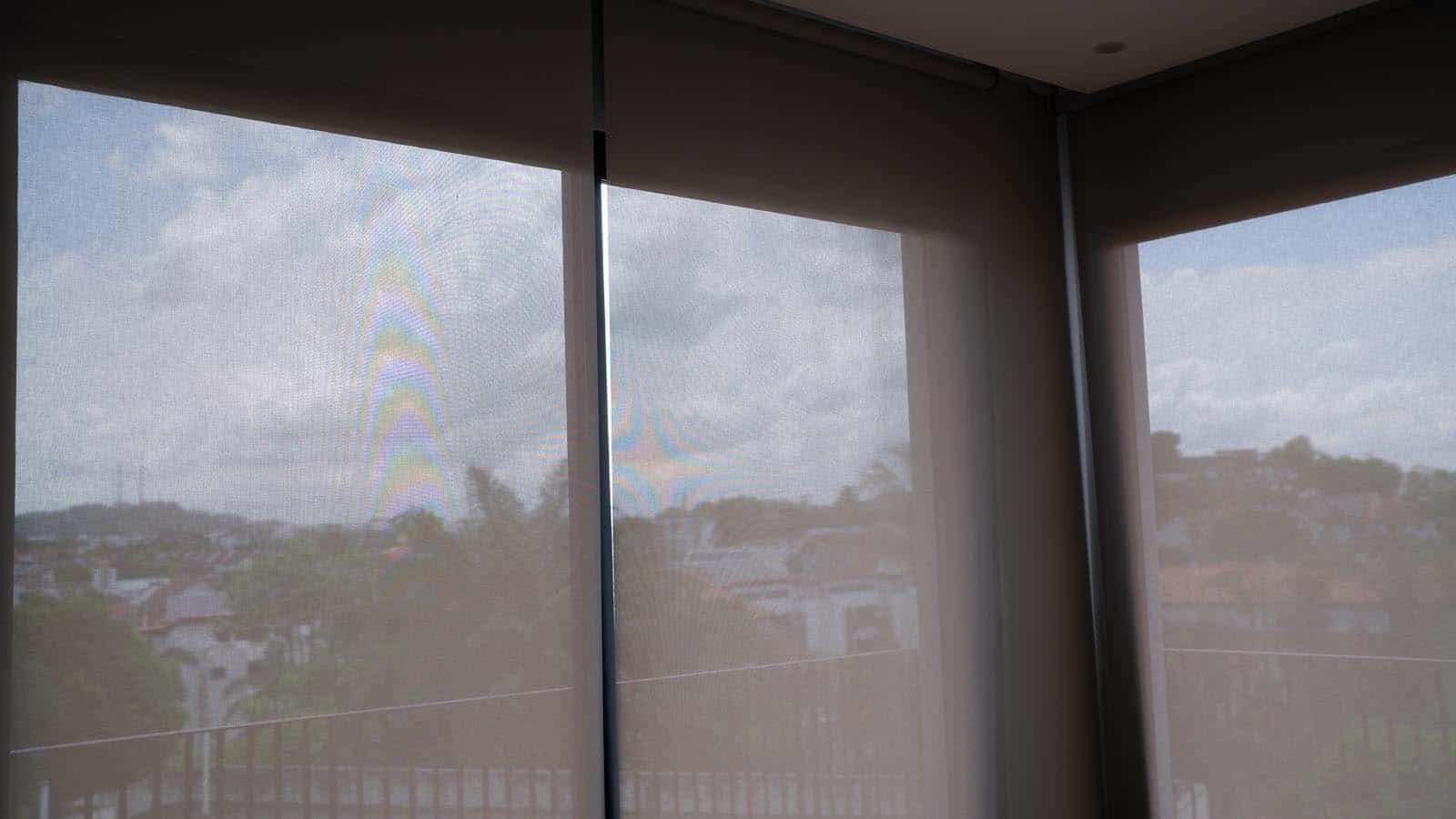 Screen roller blinds installed across a corner office